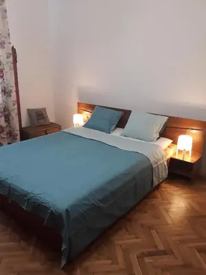 a bedroom with a large blue bed with two lamps at 500 steps to the sand in Varna City