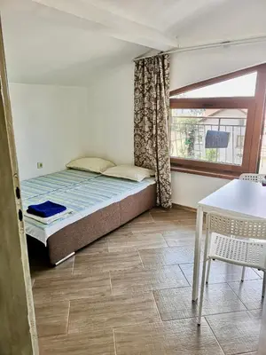 a bedroom with a bed and a table and a window at Paunovi Guest House in Primorsko