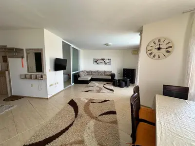 a living room with a clock on a wall at PSB Apartments in Midia Resort Aheloy in Aheloy