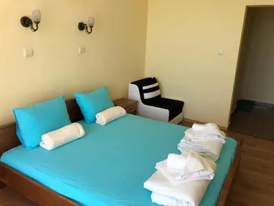 a bedroom with a blue bed with blue pillows and a chair at Family Hotel Littoral in Sozopol