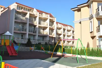 a playground in front of a large apartment building at Antorini Apartments in Sveti Vlas