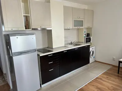 a kitchen with white cabinets and a black and white refrigerator at Antorini Apartments in Sveti Vlas