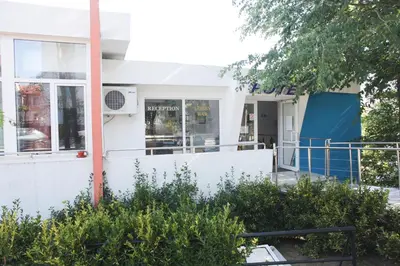 a white house with a white fence and trees at Ribarska Sreshta Family Hotel in Tsarevo