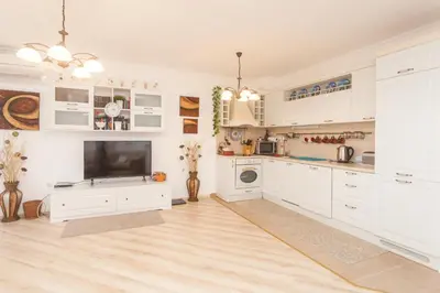 a large kitchen with white cabinets and a tv at Dom-El Real Apartments Amphora in Sveti Vlas