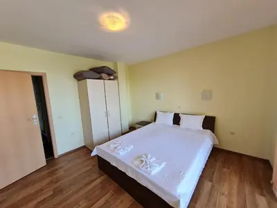 a bedroom with a large bed with white sheets at Oasis Beach Apartments Kamchia in Kamchia