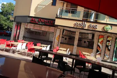 a restaurant with tables and chairs in front of a building at Menada Midia Apartments in Sunny Beach