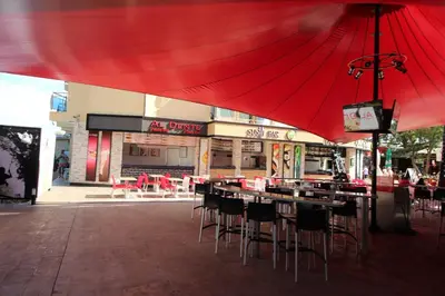 a restaurant with tables and chairs under a red umbrella at Menada Midia Apartments in Sunny Beach