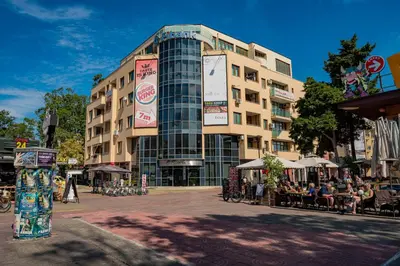 a large building with people sitting outside of it at Menada Midia Apartments in Sunny Beach