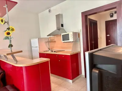 a small kitchen with red cabinets and a microwave at Menada Miramar Palace Apartments in Sunny Beach