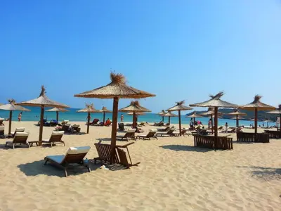 a beach with chairs and umbrellas and the ocean at Menada Miramar Palace Apartments in Sunny Beach