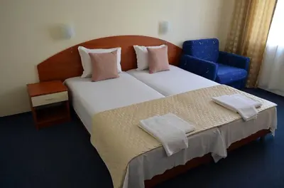 a bedroom with a large bed and a blue chair at Family Hotel Diana in Pomorie