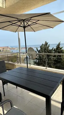 a wooden table with an umbrella on a balcony at Black Sea Apartment in Nesebar