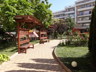 two benches in a park with a building in the background at studio Grand Kamelia in Sunny Beach