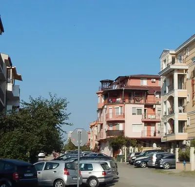 a parking lot with cars parked in front of a building at Dunav Apt.1 in Ravda