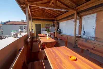 a porch with wooden tables and benches on a roof at Fener Guest House in Pomorie