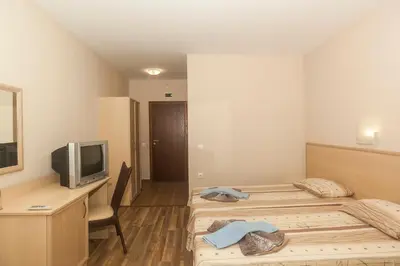a hotel room with two beds and a television at Ravda Bay Guest House in Ravda