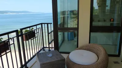 a balcony with a chair and a view of the ocean at Oasis Beach Studios in Sunny Beach