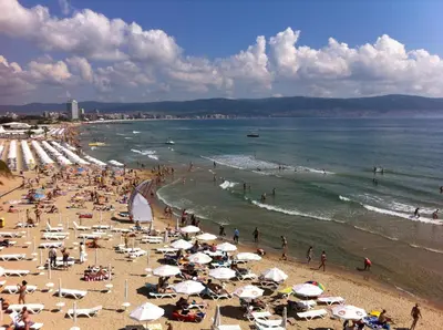 a group of people on a beach with umbrellas at Oasis Beach Studios in Sunny Beach