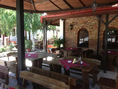 a patio with wooden tables and chairs and a brick building at Complex Astra in Sunny Beach