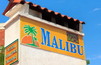 a sign on the side of a building with a palm tree at Hostel Malibu in Sunny Beach