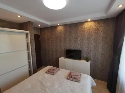 a bedroom with a bed and a tv on a wall at City Center Lux Apartment in Varna City