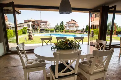 a dining room with a table and chairs and a pool at Семеен хотел