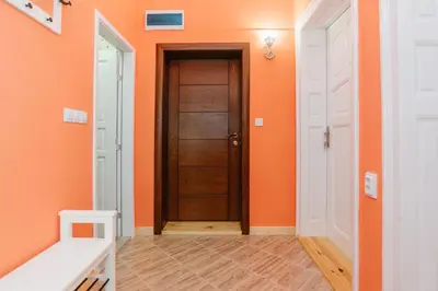 a hallway with orange walls and a wooden door at Апартамент ELSOR in Burgas City