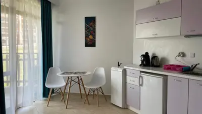 a kitchen with white cabinets and a table and chairs at FREGATA 15 Studio Sveti Vlas in Sveti Vlas