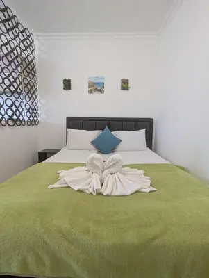 a bed with a green comforter with two white towels at FREGATA 15 Studio Sveti Vlas in Sveti Vlas