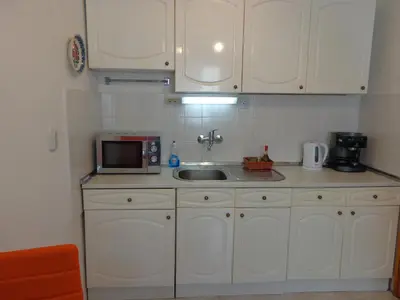 a kitchen with white cabinets and a sink and a microwave at Zoya Apartment in Burgas City