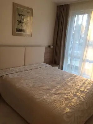 a bedroom with a large bed with a window at Апартамент Мони in Burgas City