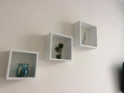 three white shelves on a wall with vases on them at Апартамент Мони in Burgas City