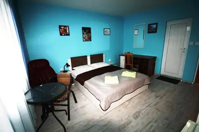 a bedroom with a bed and a table and blue walls at Zoya Guest House in Ravda