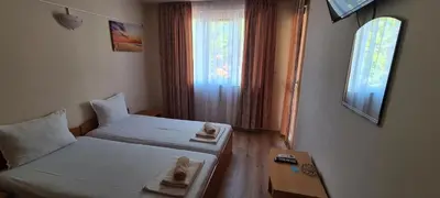 a room with two beds and a table and a window at Sineva Guest House in Ravda