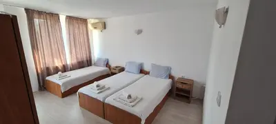 a hotel room with two beds and a window at Sineva Guest House in Ravda