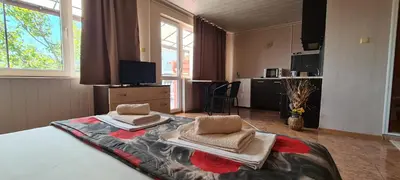 a bedroom with a bed with two chairs on it at Sineva Guest House in Ravda