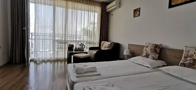 a bedroom with a bed and a chair and a window at Вила Лазурен бряг in Chernomorets