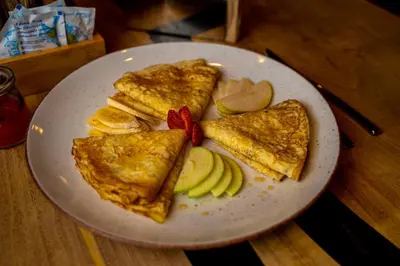 a plate of food with an omelet and apple slices at Utopia Forest in Burgas City