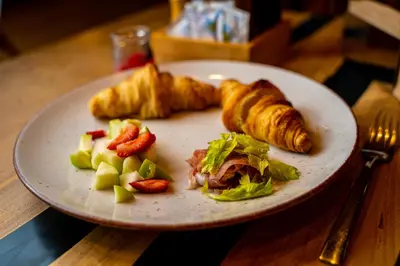 a plate of food with croissants and vegetables on a table at Utopia Forest in Burgas City