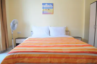 a bedroom with a bed with a colorful striped blanket at Ivanka Guest House in Obzor