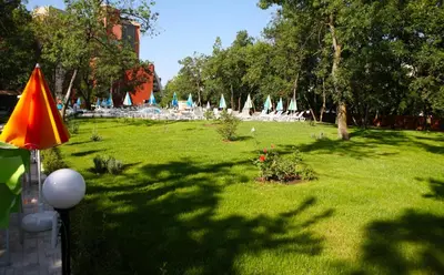 a lawn with umbrellas and chairs in a park at Hotel Yunona - All Inclusive in Sunny Beach