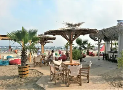 a patio with tables and chairs on the beach at Seaside Garden Apartment with 2 BR for up to 5 pax in Sunny Beach