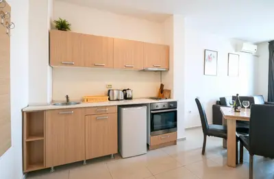 a kitchen with wooden cabinets and a table with chairs at Seaside Garden Apartment with 2 BR for up to 5 pax in Sunny Beach