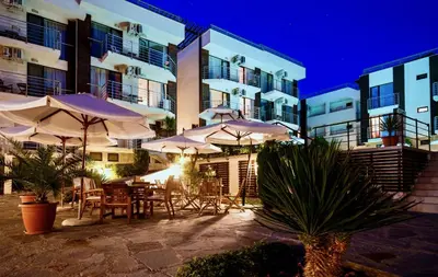a patio with tables and umbrellas in front of a building at Seaside Garden Apartment with 2 BR for up to 5 pax in Sunny Beach