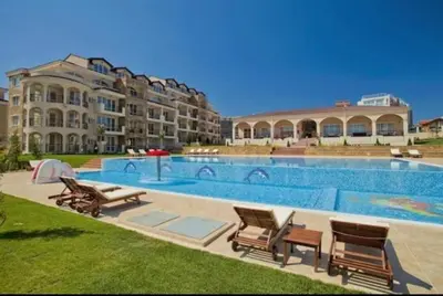 a swimming pool with chairs and a large building at Apartments in complex ATIA RESORT in Chernomorets