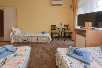 a hotel room with two beds and a flat screen tv at Kazlarov Guest House in Kiten