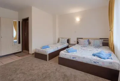 a bedroom with two beds with blue pillows at Kazlarov Guest House in Kiten