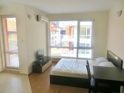 a bedroom with a bed and a desk and a window at Apartments in Azalia 2 Complex in Nesebar