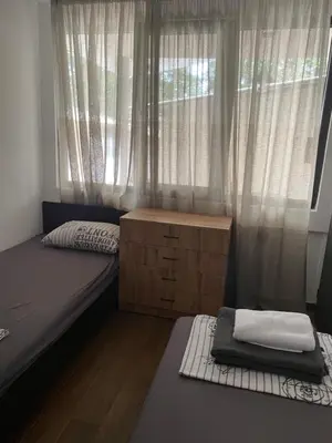 a bedroom with two beds and a window with curtains at Бунгала Виктория - Камчия in Kamchia