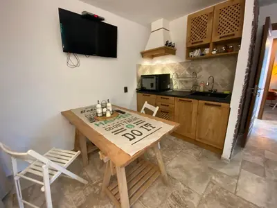 a kitchen with a wooden table and chairs and a tv at Бунгала Виктория - Камчия in Kamchia